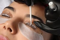 Close-up of eyelash tinting being applied to closed eyes with protective pads underneath